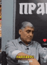 a man is sitting in front of a sign that says harvardu @snazan um