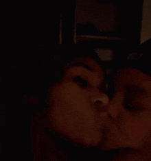 a man and woman are kissing in the dark .