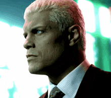 a close up of a man 's face with a green light behind him