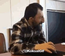 a man with a beard is sitting at a table with a computer mouse .