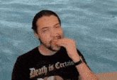 a man wearing a shirt that says certain is eating a snack