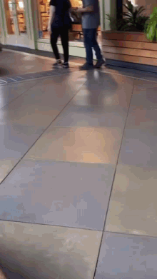 a blurred image of people walking on a tiled floor in a mall .