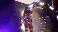 a woman in a wrestling outfit with a belt around her waist is standing in a dark room .