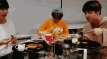 three people are sitting at a table eating food with chopsticks .