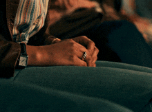 a person wearing a watch and a ring holds their hands together