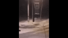 a man is walking down a snowy street at night .