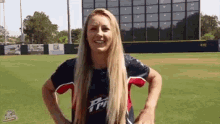a woman in a baseball uniform is standing on a baseball field .