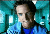 a man in a blue jacket is smiling in a hospital