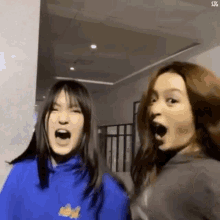 two girls are standing next to each other with their mouths open and making funny faces .