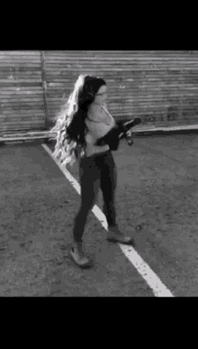 a woman with long hair holding a gun in a parking lot