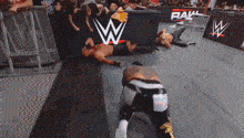 two wrestlers are laying on the floor in a wrestling ring with a w logo in the background