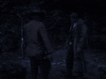 a person is standing in a dark forest near a body of water .