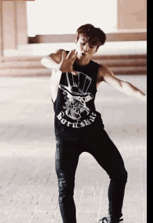 a man wearing a black tank top that says ' boys ' on it is dancing