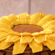 a cake decorated to look like a sunflower is being covered in yellow frosting