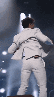a man in a white suit dancing on a stage