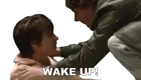 a man holds a woman 's face and says wake up in white letters