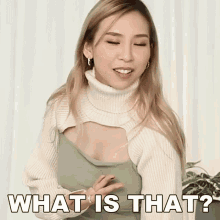 a woman wearing a white sweater and a green top is asking what is that ?