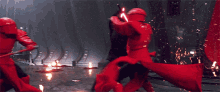 a man in a red suit is holding a red lightsaber while fighting a group of red guards .