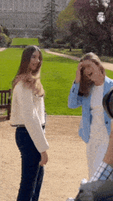 two women are standing next to each other in a park and one of them is wearing a blue jacket