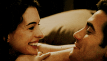 a man and a woman are laying on a bed and the woman is smiling
