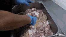 a person wearing blue gloves is putting meat in a container .