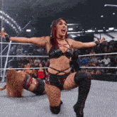 a female wrestler is kneeling down with her arms outstretched in front of a crowd