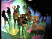 a blurry picture of people dancing in a club with a man wearing a shirt that says ' a ' on it