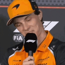a man wearing a mclaren hat is holding a microphone .