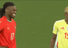 a soccer player wearing number 19 stands next to a player wearing number 17
