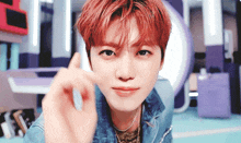 a close up of a young man with red hair making a heart shape with his hand .