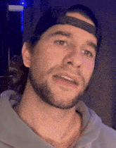 a man with a beard wearing a baseball cap and a necklace