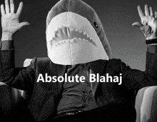 a man in a suit has a stuffed shark head on his head and the words absolute blahaj below him