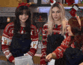 three women wearing christmas sweaters with the letter t on them