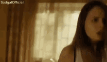 a woman is standing in front of a window in a room and looking at the camera .