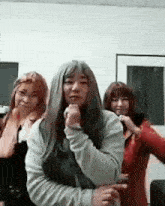 a group of women are standing next to each other in a room and one of them is wearing a wig .