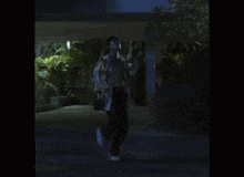 a man is walking down a dark street at night .