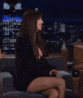 a woman in a black dress is sitting on a couch