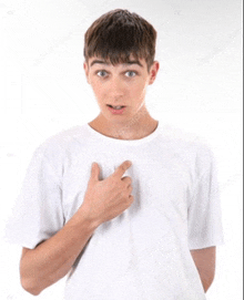 a young man in a white t-shirt is pointing to his chest