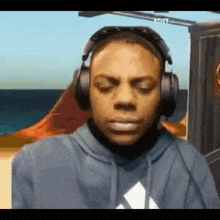 a man wearing headphones and a hoodie is making a face .