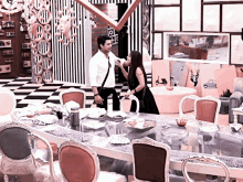 a man and a woman are standing in front of a dining table