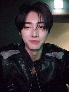 a young man wearing a black leather jacket and a black shirt .