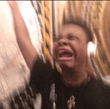 a man wearing headphones and a black shirt with the letter t on it is crying