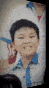 a young boy in a white shirt and blue tie smiles in a blurry photo