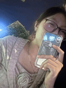 a woman wearing glasses is taking a picture of herself with her iphone