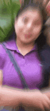 a woman in a purple shirt is sitting on a couch .