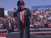 a man in a suit and tie is standing in front of a crowd holding a sign that says ' america great '