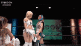 two female wrestlers stand in front of a sign that says stardom