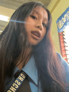 a girl with long hair is wearing a blue shirt and tie with a black strap that says gh2ch