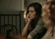 a woman sits at a table with her hand on her face