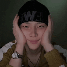 a man wearing a watch and a black beanie with the word we on it